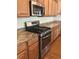 Stainless steel oven and gas range nestled between wooden cabinets and granite countertops in the kitchen at 20101 Oakflower Ave, Tampa, FL 33647