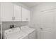 Bright laundry room with white washer, dryer, cabinets, and a door at 22359 Storybook Cabin Way, Land O Lakes, FL 34637