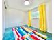 Bright bedroom with neutral walls, a window with yellow curtains, and a colorful striped rug at 2707 56Th S St, Gulfport, FL 33707
