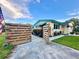 View of the house with a wooden fence, open gate, lawn, and beautiful landscaping under a blue sky at 2707 56Th S St, Gulfport, FL 33707