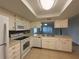 Open kitchen featuring all white appliances, tile floors, and a pass through to the living room at 2900 Grovewood Blvd # A, Palm Harbor, FL 34683