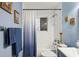 A stylish bathroom with soft blue walls, a tub with shower, framed pictures, and elegant fixtures at 3113 Chamblee Ln, Clearwater, FL 33759