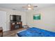 Comfortable bedroom with wood-look floors, ceiling fan, and tv above an electric fireplace at 3113 Chamblee Ln, Clearwater, FL 33759