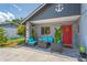 Front porch with outdoor seating area with stone pillars, a red door, and inviting decor at 3113 Chamblee Ln, Clearwater, FL 33759