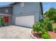 Garage with white door, complemented by landscape features, and a red front door at 3113 Chamblee Ln, Clearwater, FL 33759