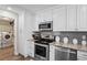Modern kitchen with stainless steel appliances, granite counters, gray subway tile backsplash, and view of laundry room at 3113 Chamblee Ln, Clearwater, FL 33759