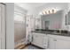 Bright bathroom featuring dual sinks, granite counters, and a tiled shower with a decorative shower curtain at 3115 Gina Ct, Holiday, FL 34691