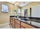 Bathroom with dark wood cabinets, black countertop, large mirror and double sinks at 3241 Evening Breeze Loop, Wesley Chapel, FL 33544