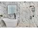 Bathroom featuring soaking tub, stone floor walk-in shower, and marble style walls at 3241 Evening Breeze Loop, Wesley Chapel, FL 33544