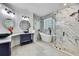Bright bathroom with a freestanding tub, and a glass enclosed walk-in shower and marble style walls at 3241 Evening Breeze Loop, Wesley Chapel, FL 33544