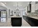 Contemporary kitchen features a large island with a sink, black cabinets, modern lighting, and tile flooring at 3241 Evening Breeze Loop, Wesley Chapel, FL 33544