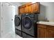 Modern laundry room with new washer, dryer, utility sink, and wooden cabinets at 3241 Evening Breeze Loop, Wesley Chapel, FL 33544