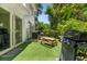 Backyard featuring artificial grass, a picnic table, a grill, and sliding glass door leading to home at 3323 Fox Hunt Dr, Palm Harbor, FL 34683