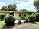 Backyard view of house with chairs on patio surrounded by lush bushes and trees at 3575 Lake Highland Dr, Palm Harbor, FL 34683