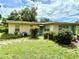 Back view of single-story home with lawn and lush greenery surrounding the house at 3575 Lake Highland Dr, Palm Harbor, FL 34683