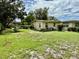 Back and side view of house shows the spacious yard with leafy trees at 3575 Lake Highland Dr, Palm Harbor, FL 34683