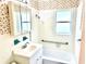 Bright bathroom with white tile, vanity, tub, and floral wallpaper at 3575 Lake Highland Dr, Palm Harbor, FL 34683