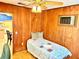 Cozy bedroom with wood-paneled walls, and a view into the kitchen at 3575 Lake Highland Dr, Palm Harbor, FL 34683