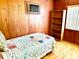 Small bedroom featuring wood-paneled walls, a bed with a patterned quilt, and a bookshelf at 3575 Lake Highland Dr, Palm Harbor, FL 34683