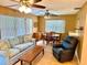 Living room featuring wood-paneled walls, comfortable seating, and two ceiling fans at 3575 Lake Highland Dr, Palm Harbor, FL 34683