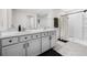 A bathroom with double sinks, shower, white cabinets and a tile floor at 36652 N Spanish Rose Dr, Dade City, FL 33525