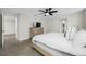 Cozy bedroom features neutral carpet, white bedding, and ceiling fan with a mounted TV at 36652 N Spanish Rose Dr, Dade City, FL 33525