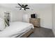 Comfortable bedroom with neutral carpet, white bedding, and ceiling fan with mounted TV at 36652 N Spanish Rose Dr, Dade City, FL 33525