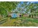 A storage shed with blue door sits in the grassy backyard with privacy fence, shaded by mature trees at 3714 N Garrison St, Tampa, FL 33619