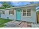 View of front exterior with bright turquoise front door, decorative shutters, and landscaped entrance at 3714 N Garrison St, Tampa, FL 33619