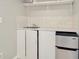 Practical laundry room equipped with shelving, a sink, and a compact stainless steel refrigerator at 3714 N Garrison St, Tampa, FL 33619
