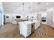 Open kitchen with an island, seating, white cabinets, pendant lights, and hardwood floors, leading into the living area at 4080 Bonfire Dr, Odessa, FL 33556