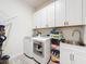 Laundry room with a stainless steel utility sink, white cabinets, and front load washer and dryer units at 4080 Bonfire Dr, Odessa, FL 33556