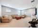 Spacious living room featuring a beige couch, an armchair, a wooden chest, and carpet flooring at 4080 Bonfire Dr, Odessa, FL 33556
