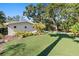 Side yard featuring a meticulously maintained artificial lawn, mature landscaping, and a modern home facade at 4722 W Laurel Rd, Tampa, FL 33629