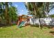 Backyard featuring a custom wooden playground structure with slide, ladder, and swings at 5107 W Azeele St, Tampa, FL 33609
