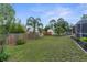 A large backyard features a mix of grass, palm trees, and wood fencing at 5112 Odin St, Spring Hill, FL 34608