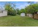 The spacious backyard is grassy, featuring a storage shed and mature trees at 5112 Odin St, Spring Hill, FL 34608