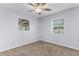 Neutral bedroom features plush carpet flooring, ceiling fan, and two windows with views at 5112 Odin St, Spring Hill, FL 34608