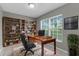 A well-lit home office featuring a wooden desk, a comfortable chair, and ample shelving for storage at 5112 Odin St, Spring Hill, FL 34608