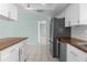 Kitchen area featuring stainless steel appliances, white cabinets, butcher block countertops, and tile flooring at 5112 Odin St, Spring Hill, FL 34608