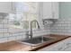 Close up of a kitchen sink with subway tile backsplash, window, and butcher block countertops at 5112 Odin St, Spring Hill, FL 34608