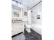 Bathroom with black and white color scheme, tiled shower, updated vanity, framed mirror and black hexagon tile flooring at 5730 Imperial Ky, Tampa, FL 33615