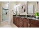 Elegant bathroom with dual sinks, granite counters, wood cabinets, and a glass-enclosed shower at 650 Geneva Pl, Tampa, FL 33606
