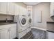 Well-lit laundry room features white cabinets, stone floors, sink, and Whirlpool washer and dryer set at 650 Geneva Pl, Tampa, FL 33606
