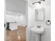 Half bathroom with pedestal sink, decorative mirror, and a view to the kitchen at 716 35Th W St, Bradenton, FL 34205