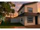 This stylish two-story home features neutral stucco, black trim, a lush green lawn, and flowering tropical tree at 8274 Rose Ter, Seminole, FL 33777