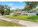 Landscaped home featuring mature trees, lush lawn, and a white garage door at 945 Winding Oaks Dr, Palm Harbor, FL 34683