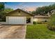 Charming one-story home featuring a well-maintained lawn, attached garage, and front porch at 945 Winding Oaks Dr, Palm Harbor, FL 34683