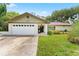 Charming one-story home featuring a well-maintained lawn, attached garage, and front porch at 945 Winding Oaks Dr, Palm Harbor, FL 34683