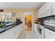 A view of the white eat-in kitchen showing the tiled floors and black countertops at 945 Winding Oaks Dr, Palm Harbor, FL 34683